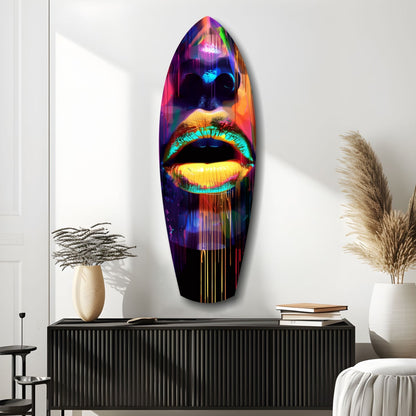 Neon-colored glass wall art depicting a stylized face with vibrant cyan lips and eyes mounted above a black console in a minimalist interior setting.