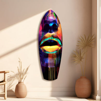 Colorful Lips V15 glass wall art mounted on beige wall, featuring neon-lit face with vibrant rainbow colors, displayed between two terracotta vases with dried plants.