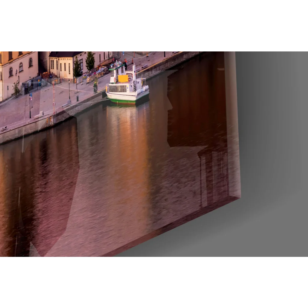 Framed glass wall art of riverboat by historic buildings in golden light