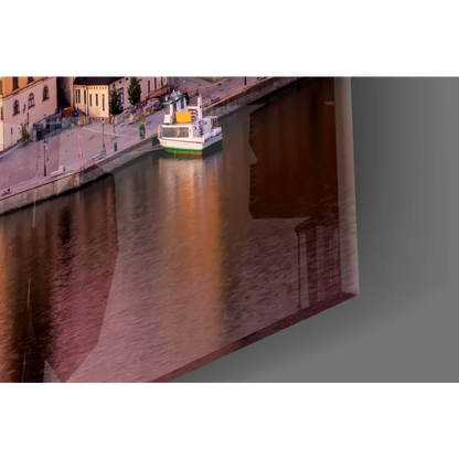 Framed glass wall art of riverboat by historic buildings in golden light