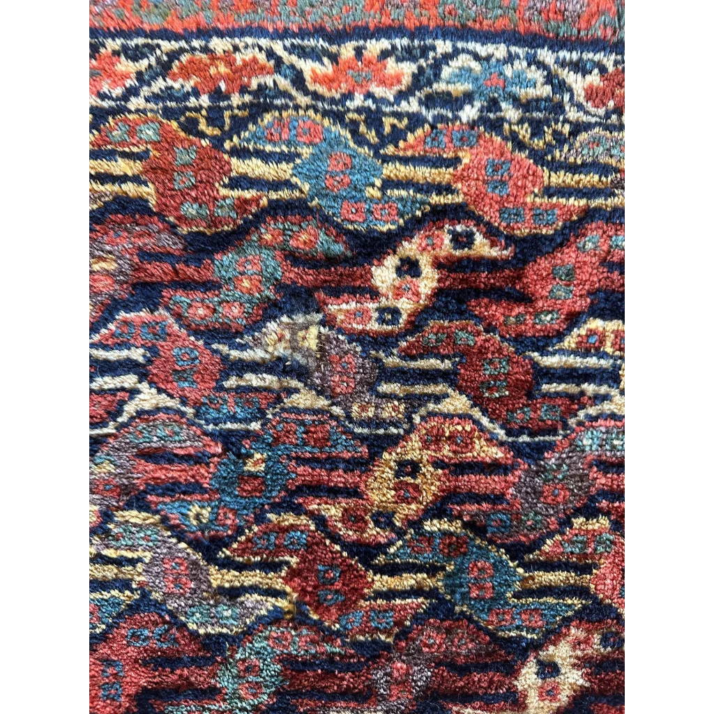 Antique Persian hanging rug 1900s, close-up of floral designs in red blue and gold, natural dyes