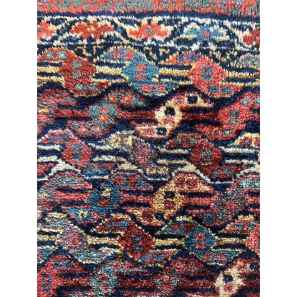Antique Persian hanging rug 1900s, close-up of floral designs in red blue and gold, natural dyes