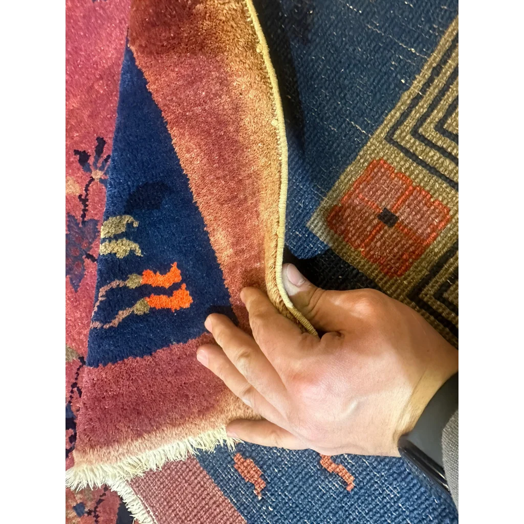 Hand holding edge of stunning Chinese art deco rug with floral vase design