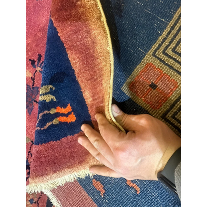 Hand holding edge of stunning Chinese art deco rug with floral vase design