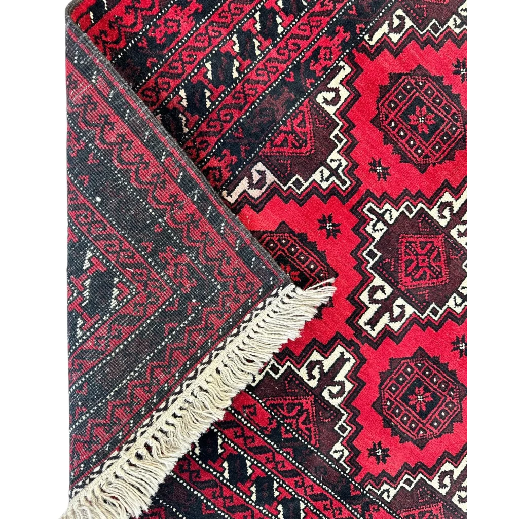 Vibrant Afghani Baluch wool rug with red black geometric patterns and cream fringe