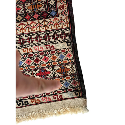 Hand touching bold geometric border of Afghani Maliki Soumak rug