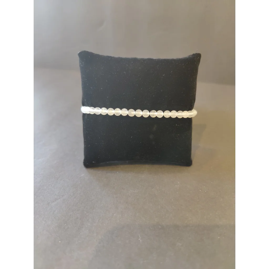 Delicate white beaded stone bracelet on black velvet cushion