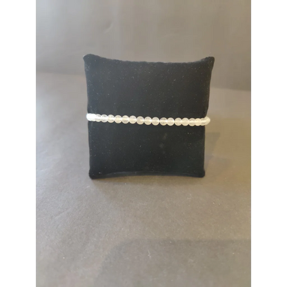 Delicate white beaded stone bracelet on black velvet cushion