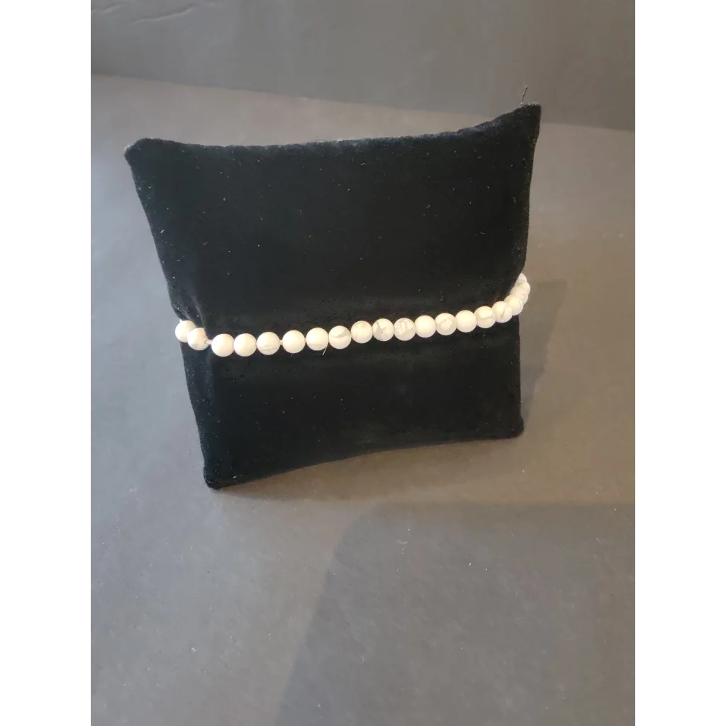 Delicate white pearl beaded stone bracelet on black velvet cushion