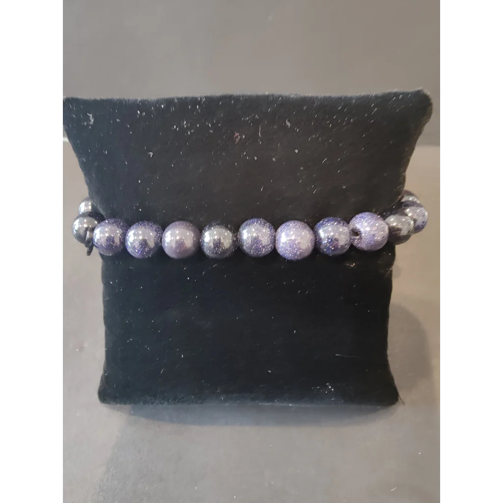 Purple silver glittery beaded stone bracelet on black velvet cushion