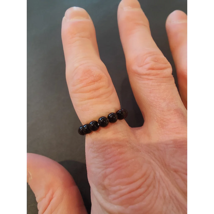 Black beaded stone ring in vibrant colors on finger