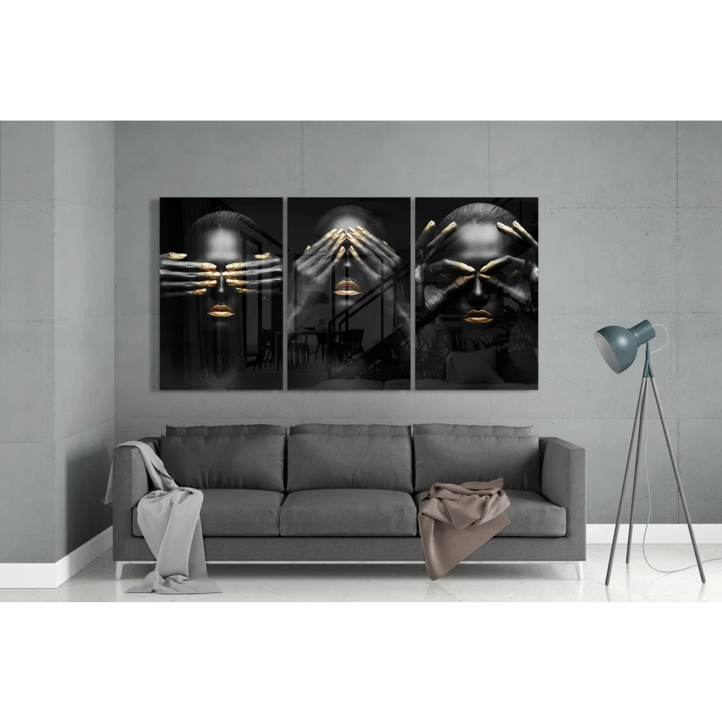 Black gold triptych glass wall art with abstract faces over gray sofa