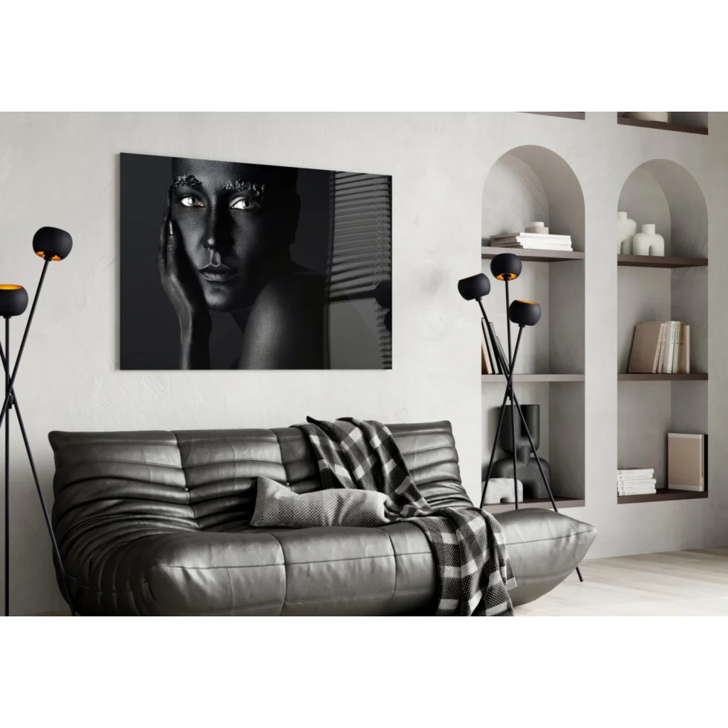 Black-and-white portrait canvas wall art with metallic detail above dark gray leather sofa