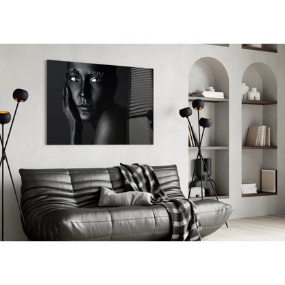 Black-and-white portrait canvas wall art with metallic detail above dark gray leather sofa