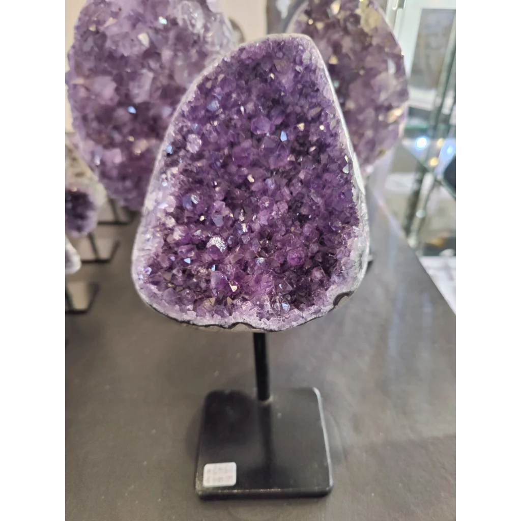 Vibrant Brazilian amethyst crystal geode on sleek black stand