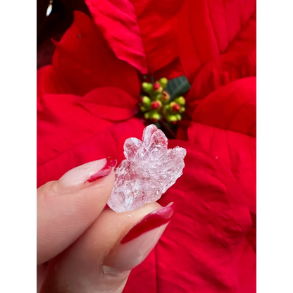Delicate fingers with red polish hold stunning Brazilian rose quartz crystal figurine