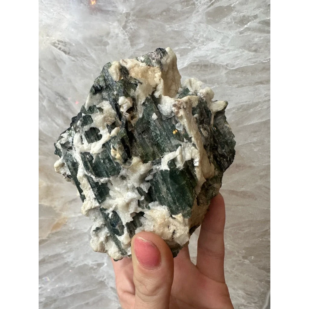 Hand holding stunning Brazilian tourmaline on albite crystals