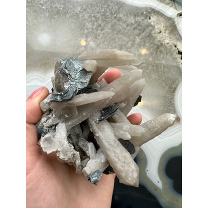 Hand holding dogtooth calcite with mica flakes and quartz crystals