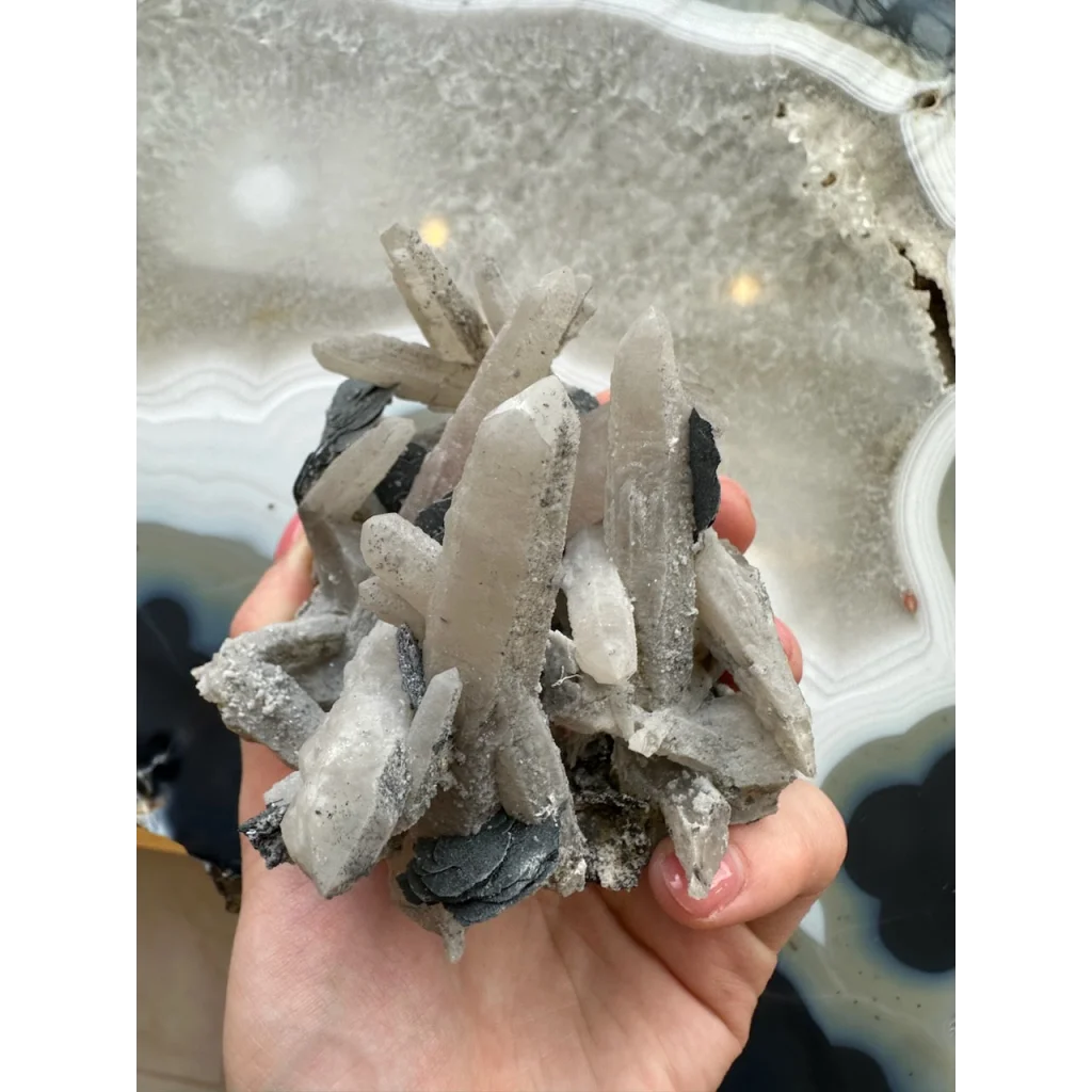 Hand holding stunning dogtooth calcite with mica flakes and quartz inclusions