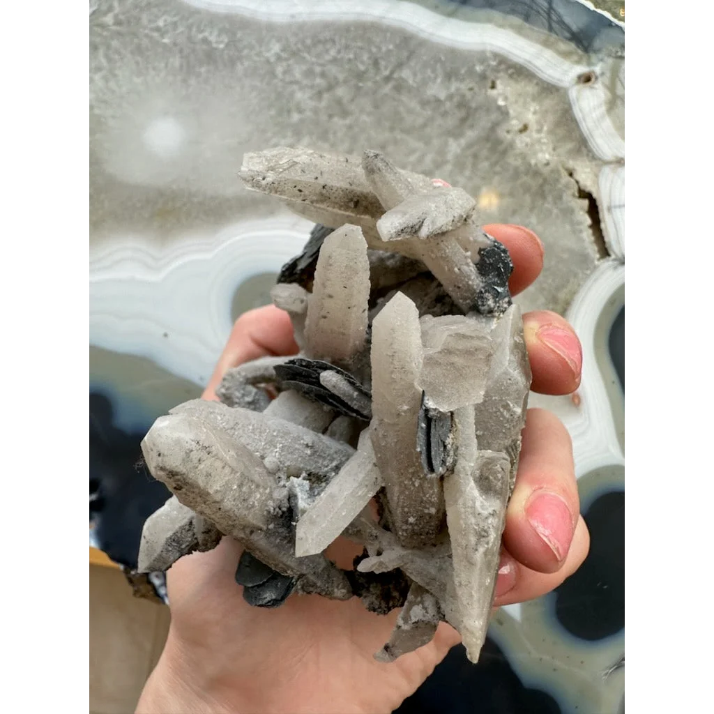 Hand holding dogtooth calcite with mica flakes and quartz crystals