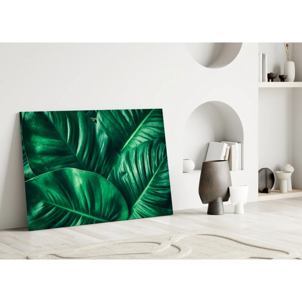 Vibrant emerald tropical leaf glass wall art leaning on white wall