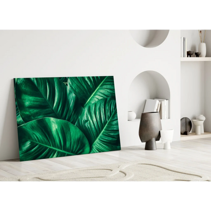 Vibrant emerald tropical leaf glass wall art leaning on white wall