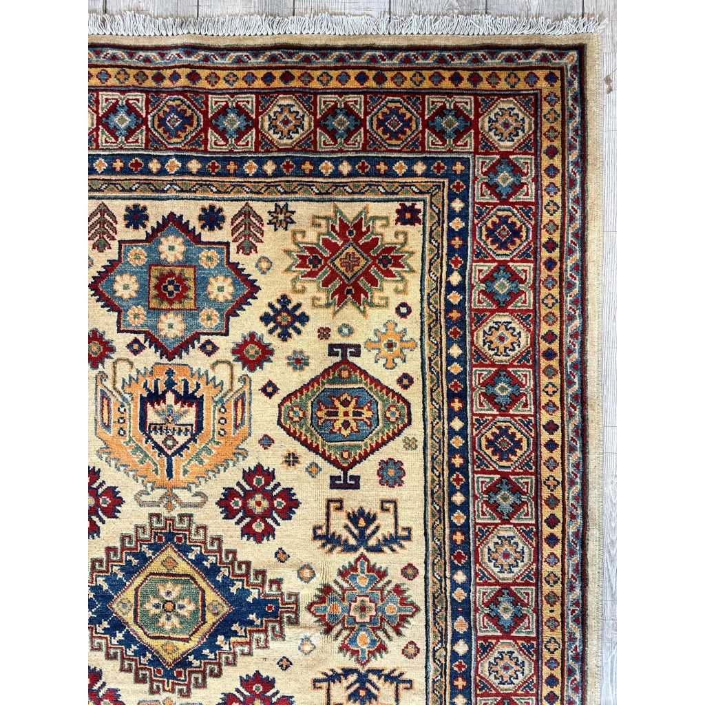 Handwoven beige Kazak rug with red, blue, gold geometric and floral patterns