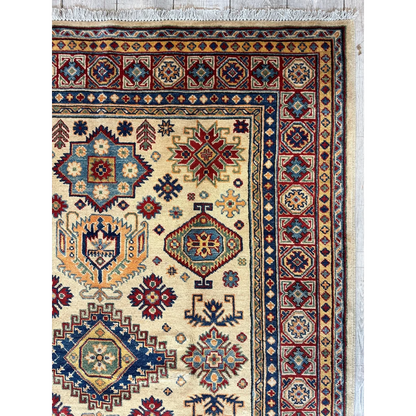 Handwoven beige Kazak rug with red, blue, gold geometric and floral patterns