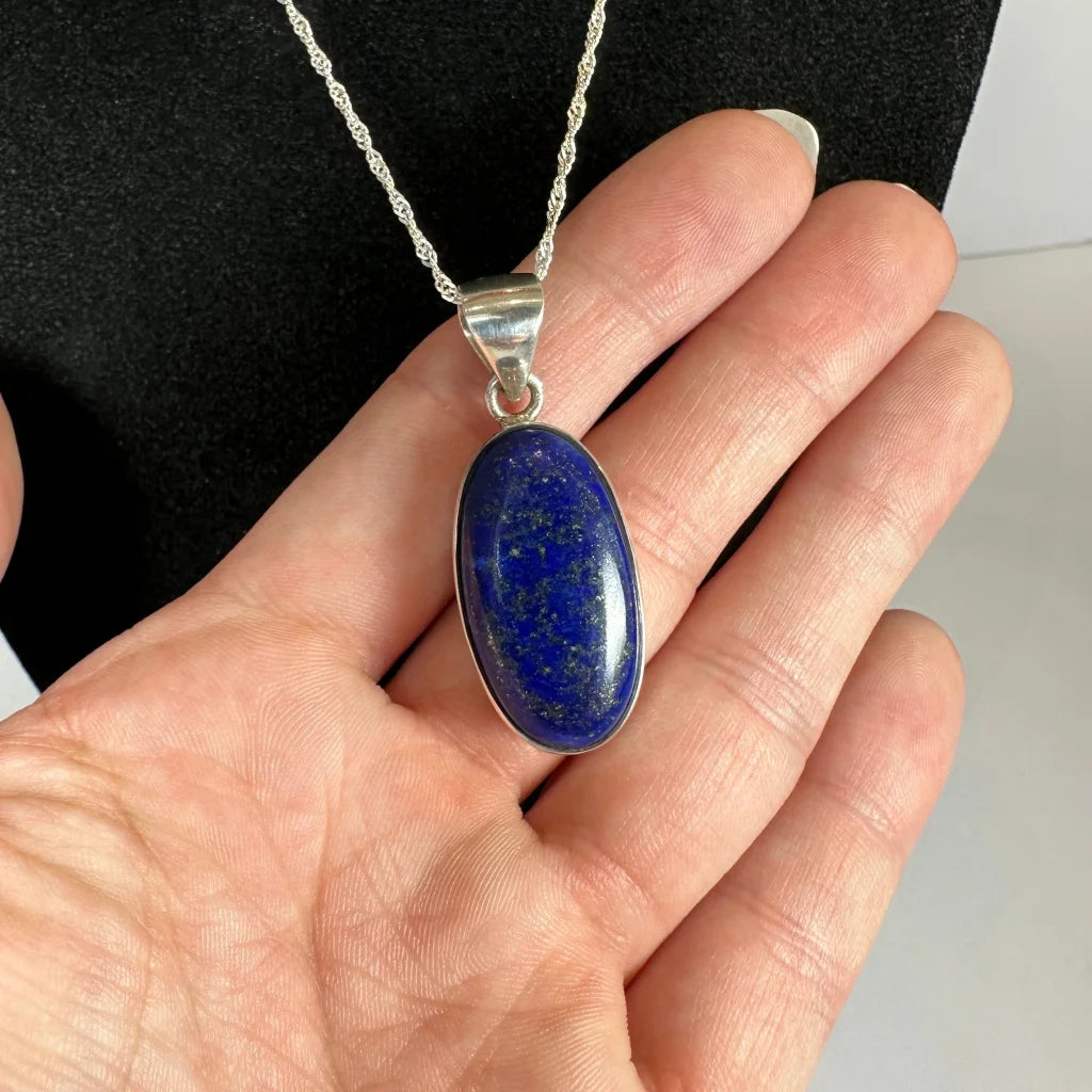 Hand holding stunning lapis lazuli pendant in sterling silver