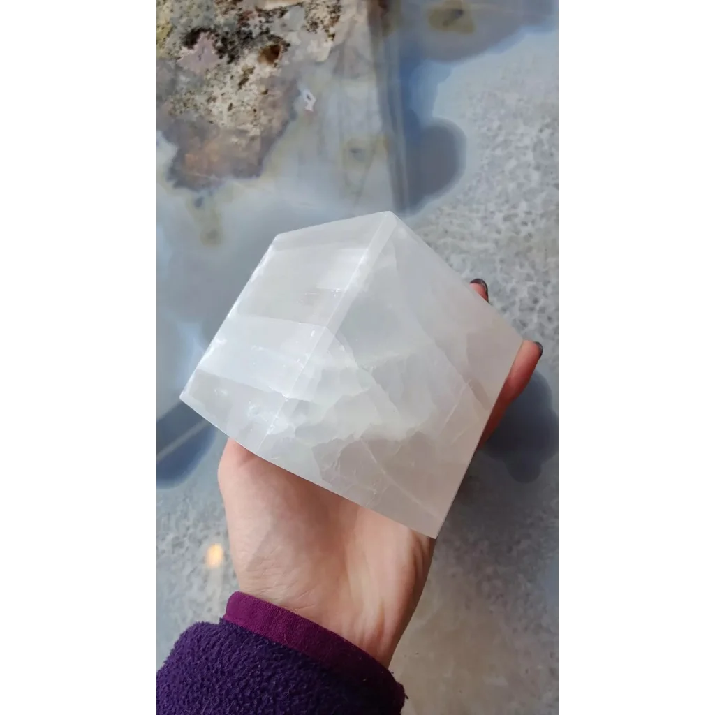 Hand holding translucent Moroccan selenite standing cube crystal