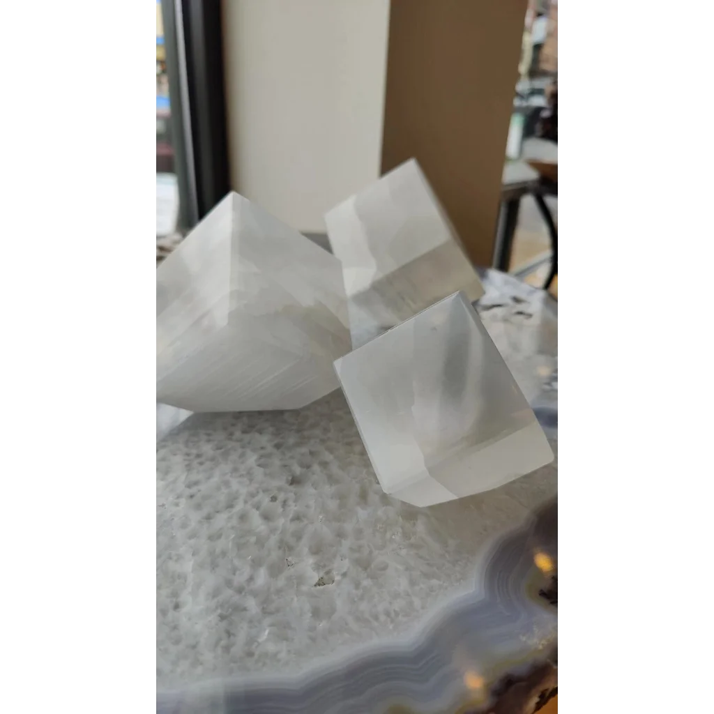Three translucent faceted selenite standing cube crystals on agate slab