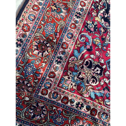 Vibrant Persian Mashhad hand knotted area rug with red floral patterns