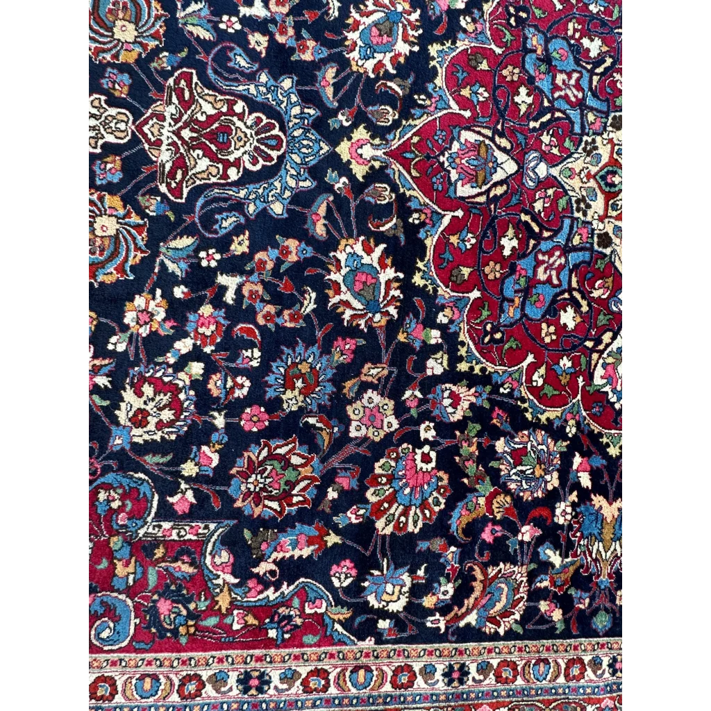 Stunning Persian Mashhad hand knotted wool area rug in dark blue with intricate floral and paisley patterns in red, pink, gold, and turquoise
