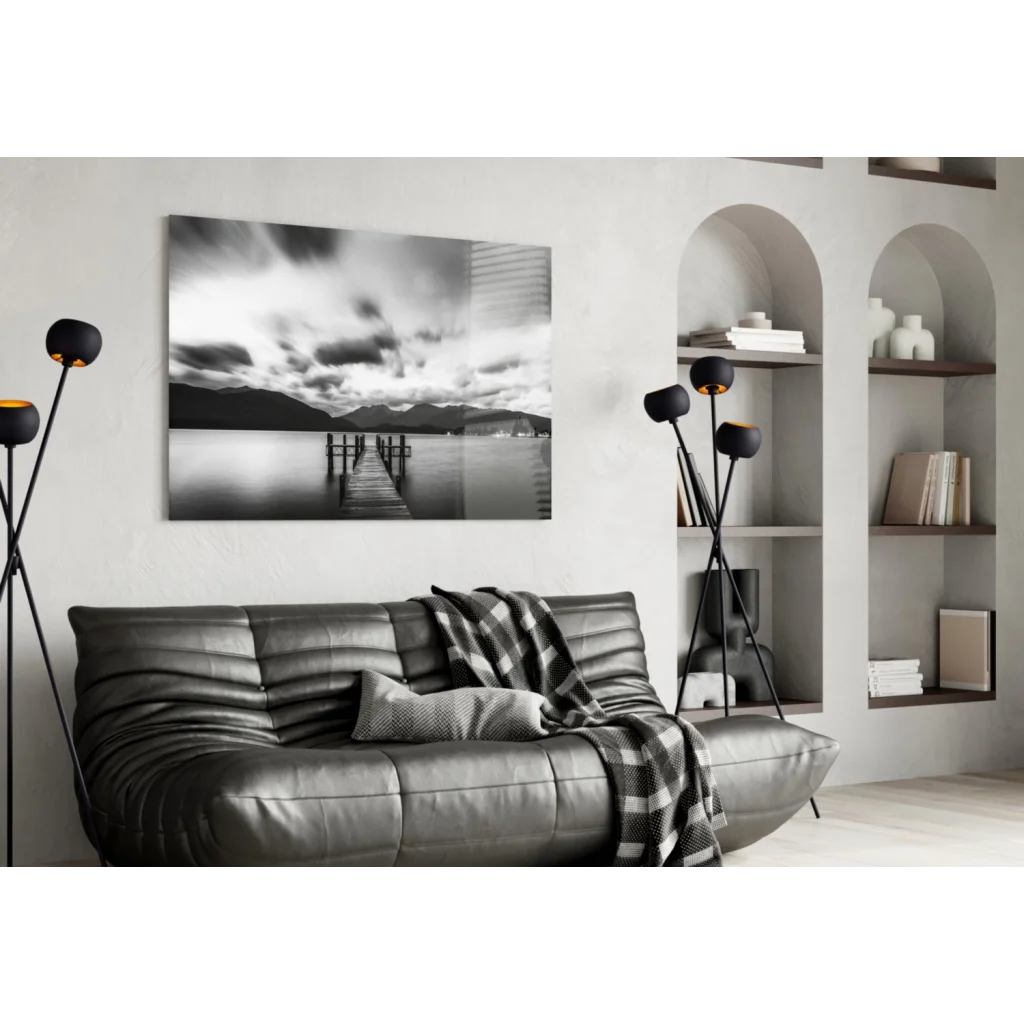 Stunning pier glass wall art with moody skies, mountains, black leather sofa, plaid throw, modern lamps