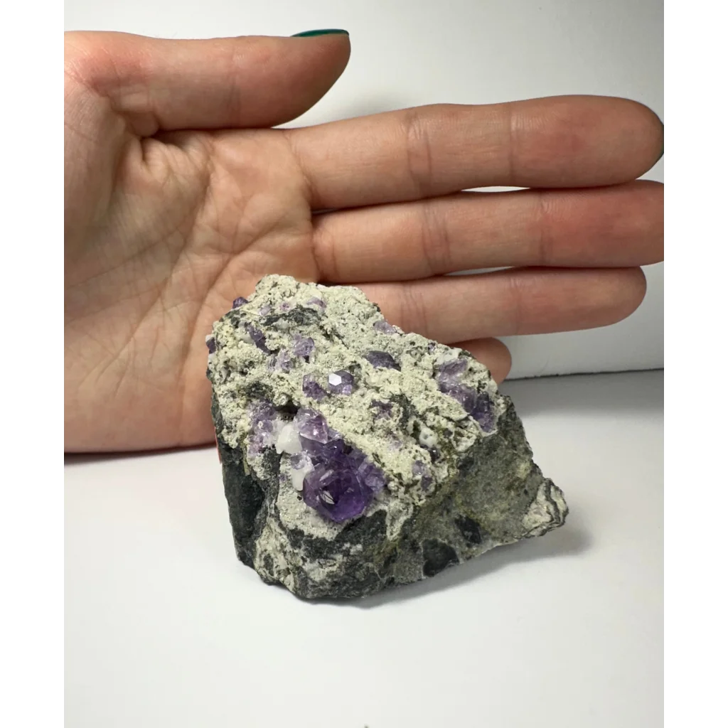 Hand holding purple fluorite clusters on natural matrix from China