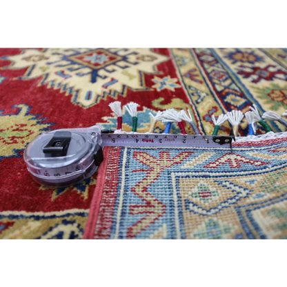 Silver tape measure on edge of Stunning Red Afghan Kazak Rug with cotton foundation