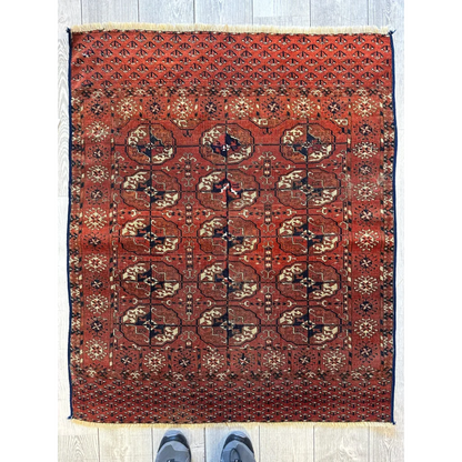 Red Turkmen Persian rug with geometric floral gul design, full view, deep red ground with cream accents