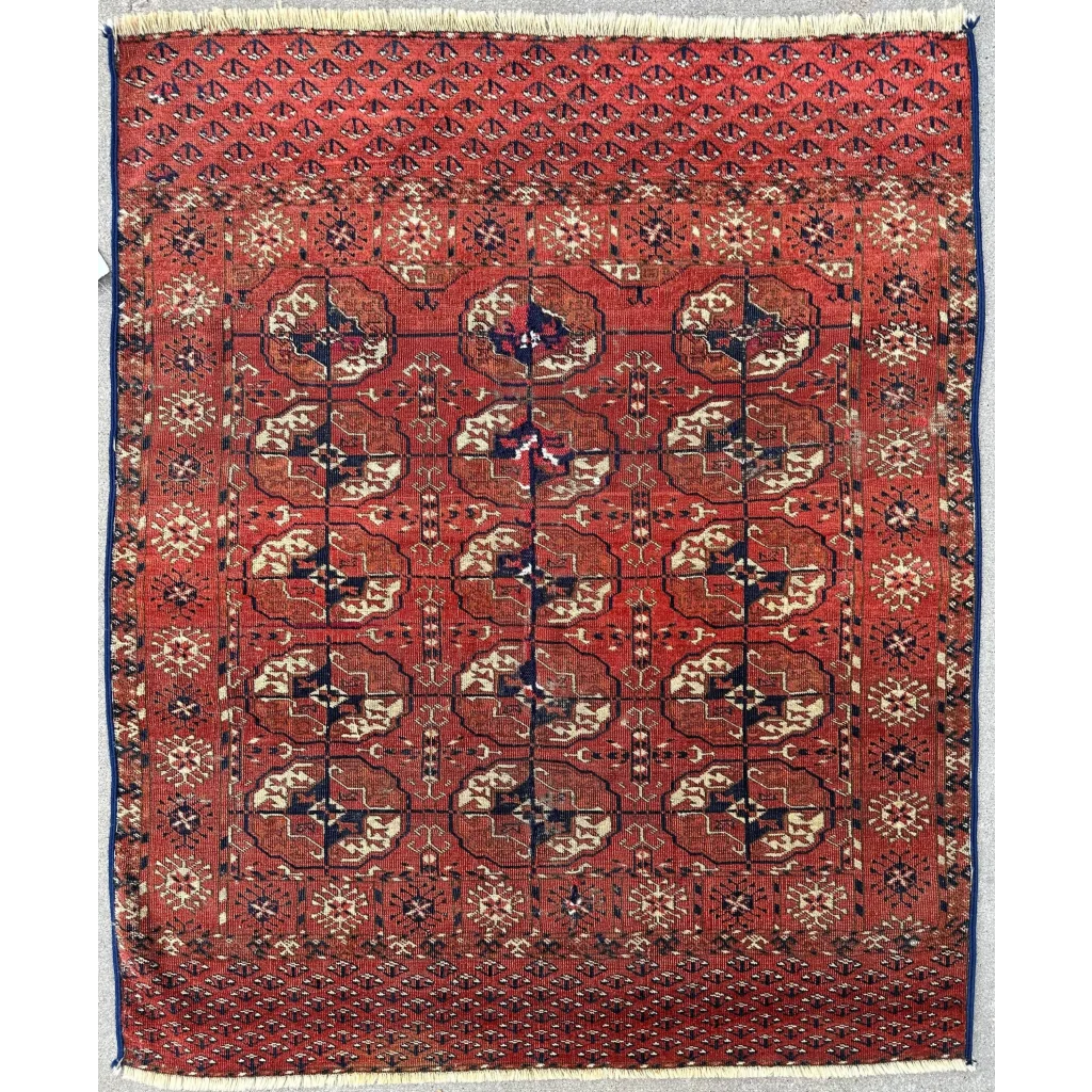Turkmen Persian rug, detail of geometric floral gul repeating field pattern, deep red and cream, hand-knotted