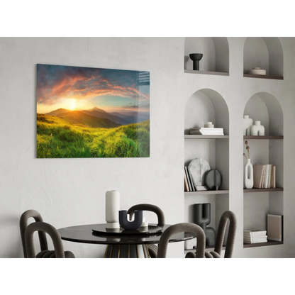 Vibrant sunset glass wall art with golden rays over green hills and mountains on white wall