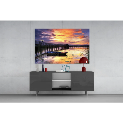 Vibrant sunset pier glass wall art with boat, calm water, and orange purple sky