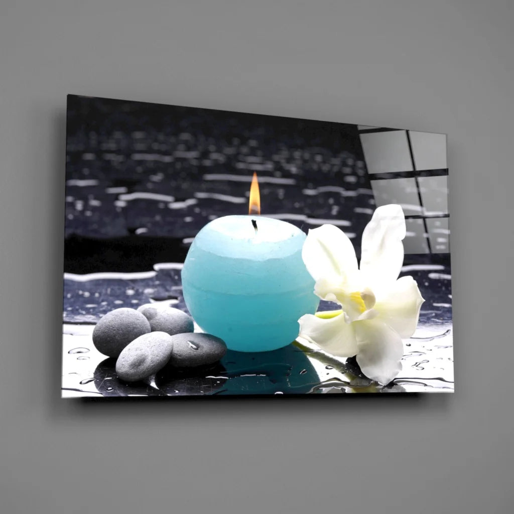 Stunning teal blue sphere candle with flame on pebbles and orchid glass wall art