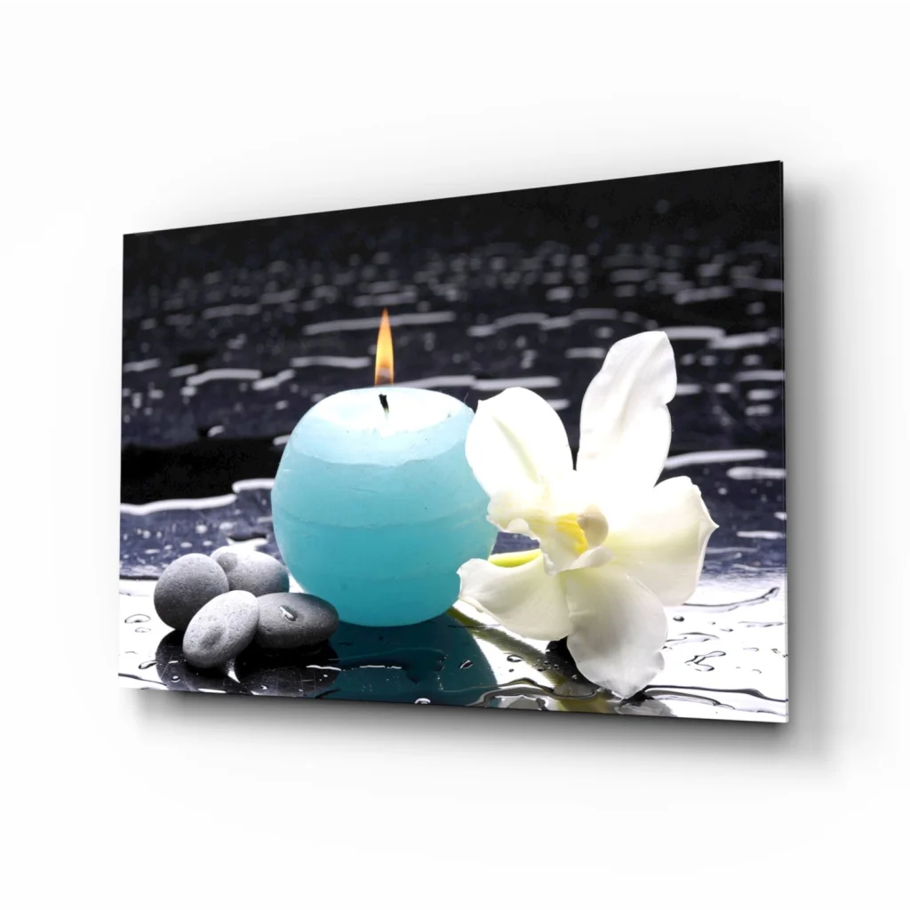 Stunning teal blue spherical candle with white orchid and pebbles on black surface glass wall art print