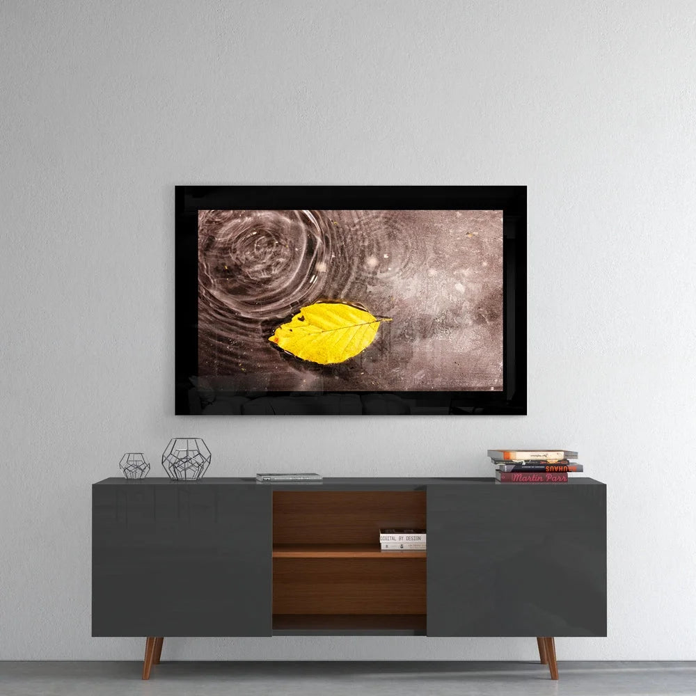 Vibrant yellow leaf on rippling water in sleek black frame glass wall art