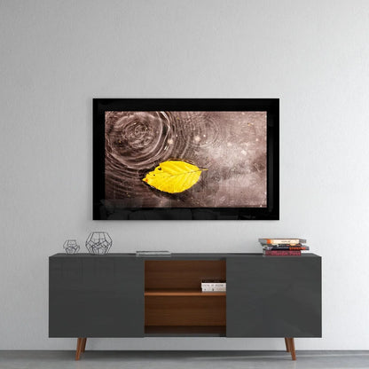 Vibrant yellow leaf on rippling water in sleek black frame glass wall art