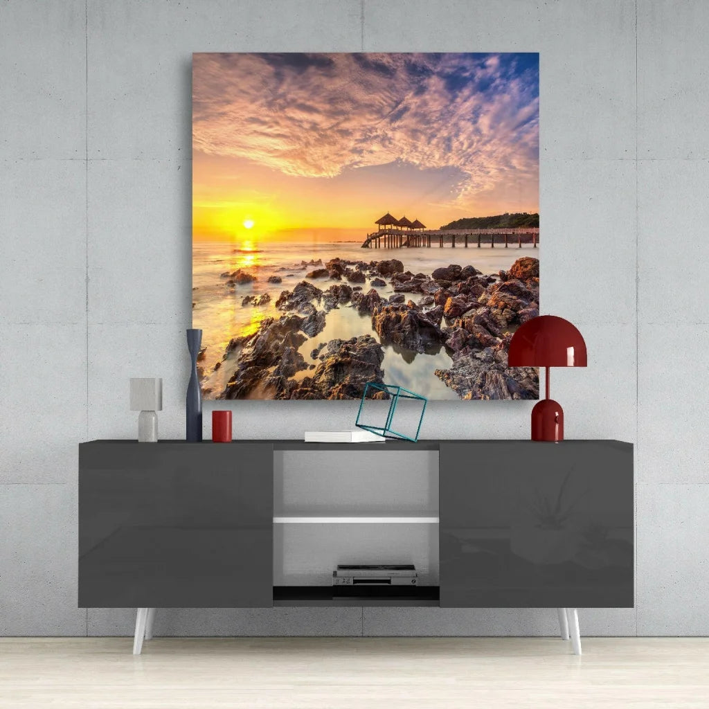 Stunning sunset glass wall art with orange hues on rocky coast