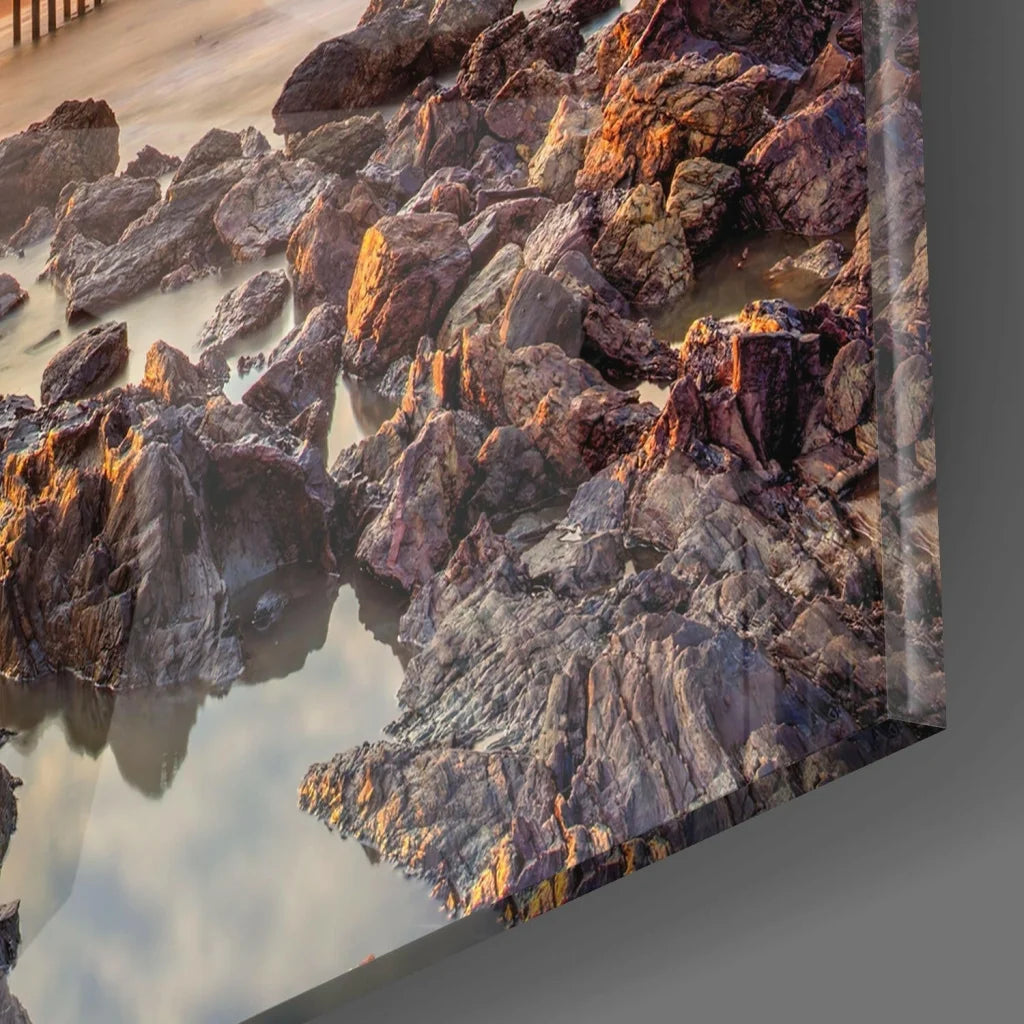 Stunning sunset glass wall art of rugged coastal rocks and water