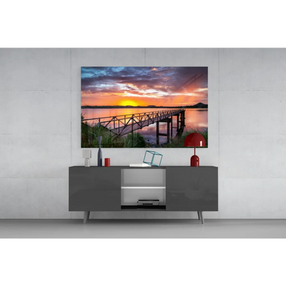 Vibrant sunset pier glass wall art over tranquil waters on gray console