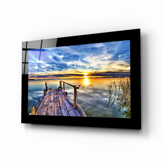 Black-framed glass wall art of sunset dock with golden water reflections