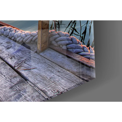 Thick braided rope on weathered dock in glass wall art with birds