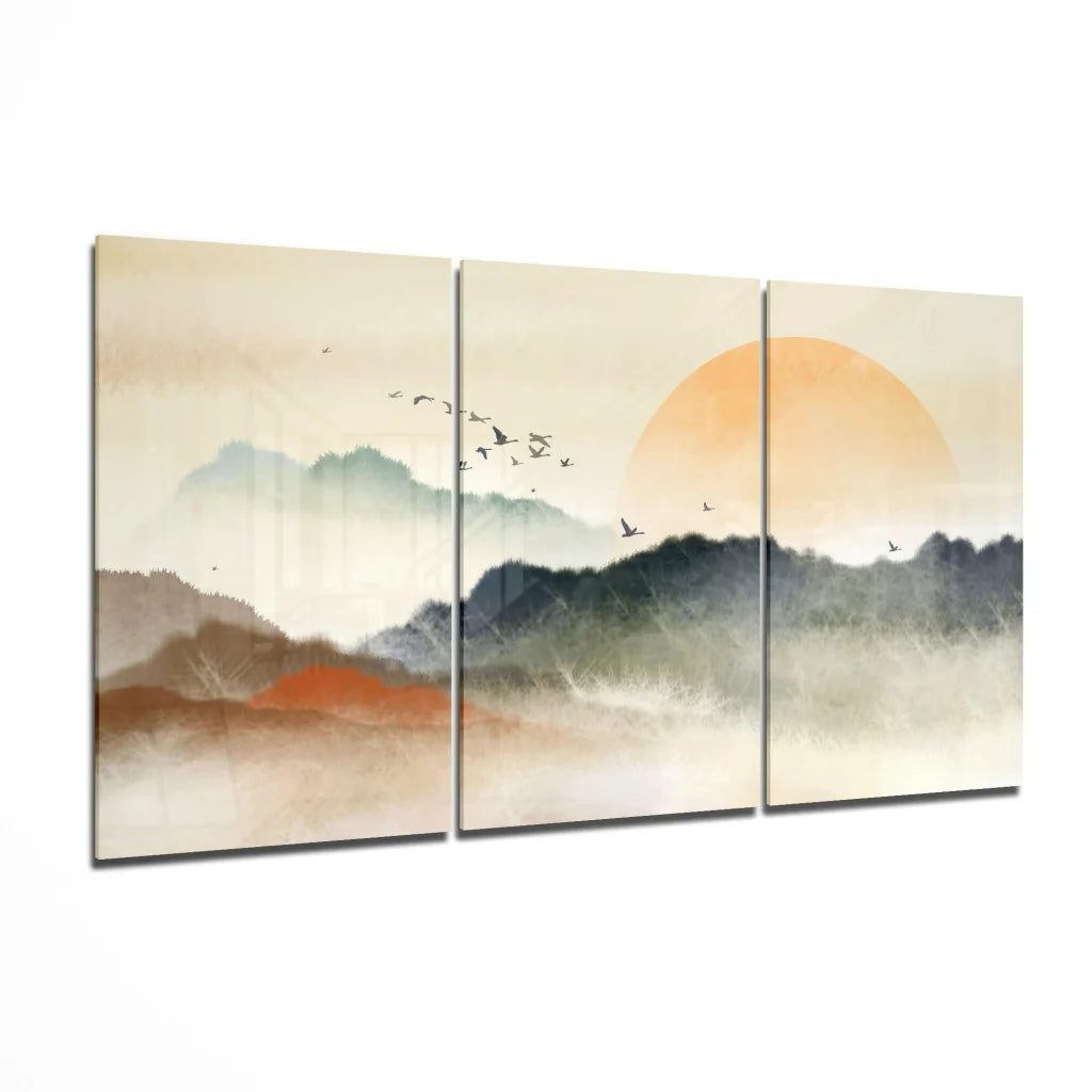 Three-panel glass wall art of misty mountains, orange sun, and birds
